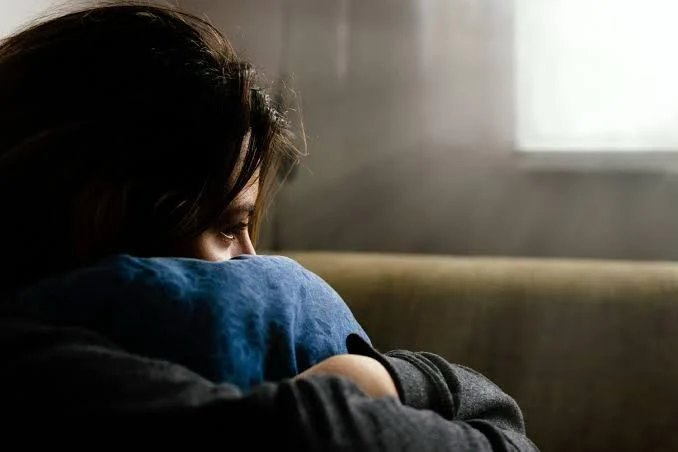 A person sitting quietly while holding a cushion