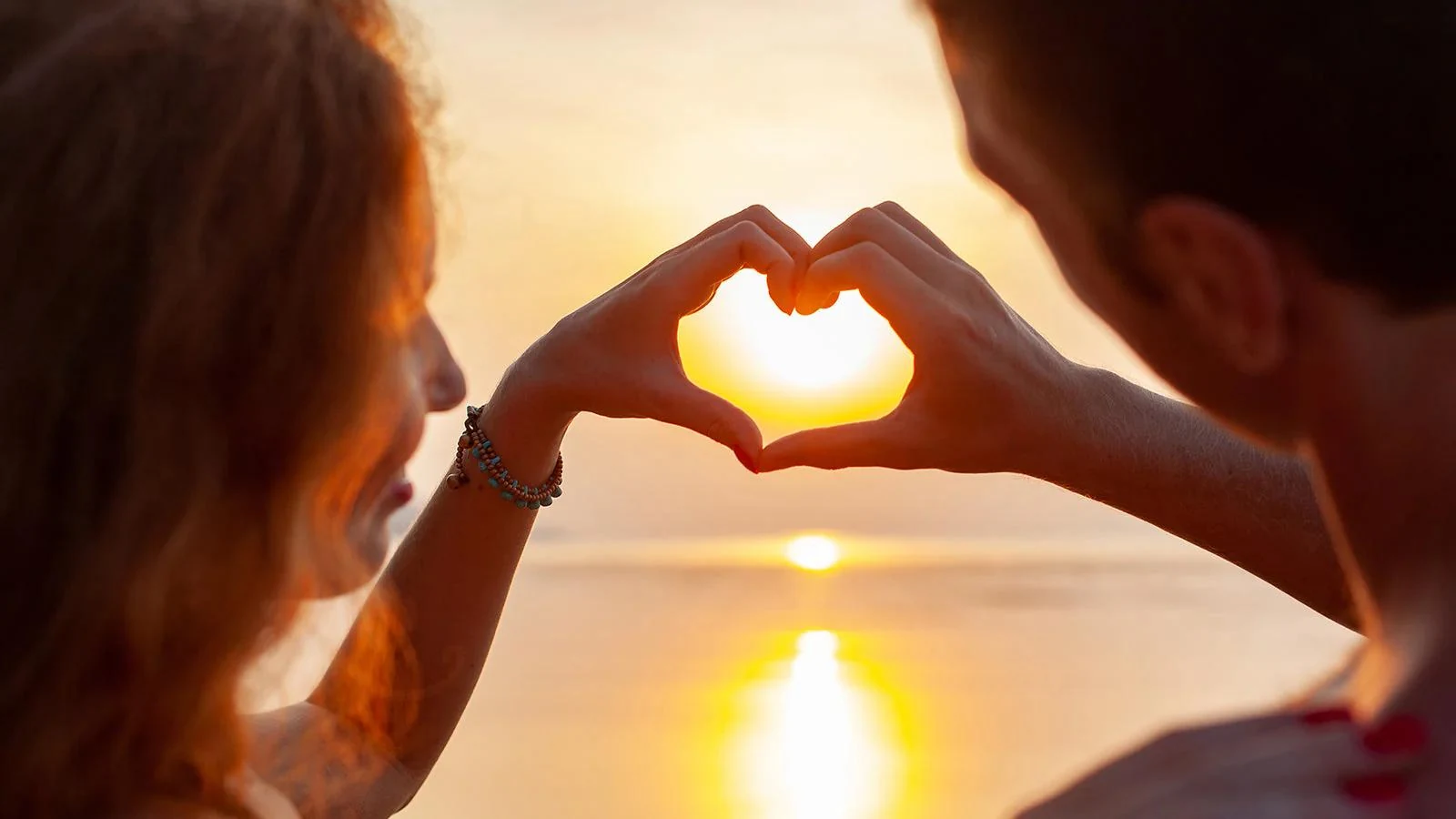 Two people forming a heart shape with their hands